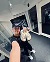 Person i sort træningstøj holder løbesko op i et lyst fitnesslokale
