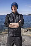 Person i Helly Hansen-lue og vest står på svaberg foran havet