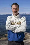 Person i Helly Hansen-fleece står på svaberg foran sjø og fjell