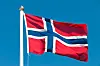 Norsk flagg som vaier fra flaggstang mot klar blå himmel