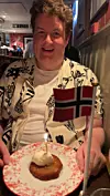 Person ved restaurantbord med dessert, tent lys og norsk flagg.