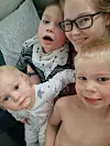 Kvinne og tre barn tett sammen i et innendørs selfie-bilde.