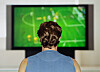 Person sett bakfra som ser en fotballkamp på TV.