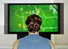 Person sett bakfra som ser en fotballkamp på TV.