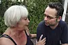 Mor og sønn snakker alvorlig sammen ute foran en grønn plantevegg.