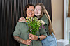 To personer står sammen innendørs og holder en bukett med fargerike blomster.
