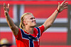 Erling Braut Haaland i rød norsk drakt jubler med armene hevet foran en rød bakgrunn.