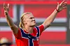 Erling Braut Haaland i rød norsk drakt jubler med armene hevet foran en rød bakgrunn.