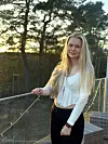 Kvinne står ved et rekkverk med lyslenker i et uteområde ved solnedgang.