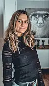 Kvinne står innendørs foran et svart-hvitt bilde av en sau.
