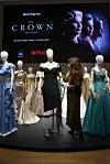 Kostymedukker med kjoler fra «The Crown» foran en stor Netflix-plakat for auksjon hos Bohemian.