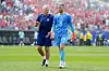 Frode og keeper Egil Selvik går på fotballbanen foran en tettpakket tribune under VM.