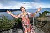 Wenche står med armene ut foran utsikten over Oslofjorden ved huset sitt i Holmestrand.