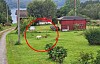To sauer ligger på en grønn plen ved et rødt uthus på et landlig tun, markert med rød sirkel.