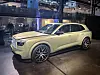 Lys grønn Volvo SUV på utstilling i et mørkt lokale med lysrigg og utstyr i bakgrunnen.